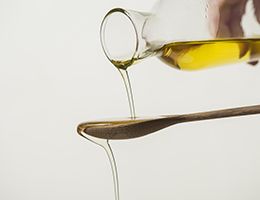 Olive oil pouring over a wooden spoon.