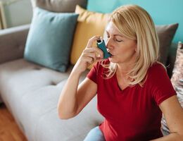 A woman uses a rescue inhaler