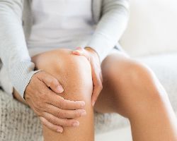 Close-up of hands holding a knee.