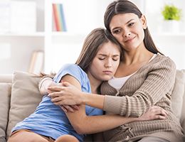 A mom comforts her teenaged daughter. 