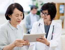  A doctor and woman look at a tablet together. 