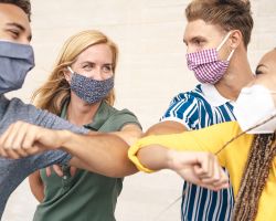 Four masked adults bump elbows.
