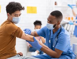 A healthcare provider gives a young man a vaccine