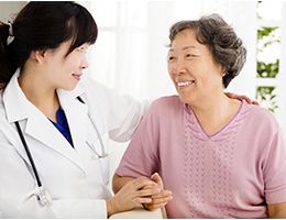 A female doctor putting her arm around a female patient.