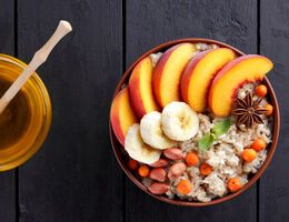 A bowl of creamy rice with fruits and nuts arranged on top.