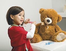 A little girl giving her teddy bear a checkup.