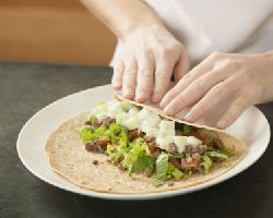 A woman folds a cucumber wrap.