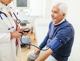 A man gets his blood pressure checked by a doctor.