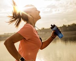 A woman runs while holding a water bottle.
