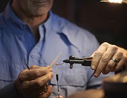 An older man tying a fly for fly fishing.