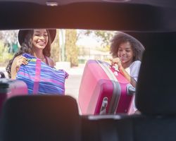  Two kids load luggage into a car.