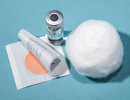 A bandage, a vial of vaccine and a cotton ball.