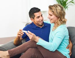 A couple smiles at a pregnancy test stick.