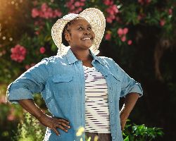 A woman stands in a garden, her hands on her hips