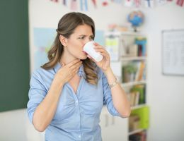 In a classroom, a teacher drinks from a cup