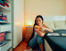 A young woman holds a phone to her glucose monitor.