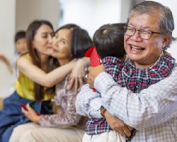A multigenerational family hugs on a couch