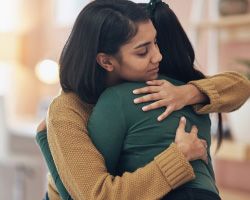 Photo of two grieving people hugging.