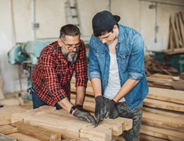 A younger and older man doing carpentry.
