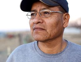 A man in a baseball cap and glasses looks off into the distance.
