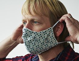 A man putting on a cloth face mask.