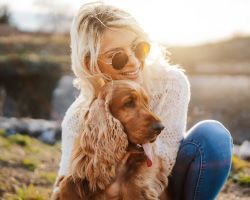 A woman pets a happy-looking spaniel.