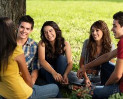 A group of young adults sits under a tree