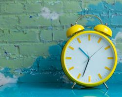 A bright yellow analog alarm clock on a table.