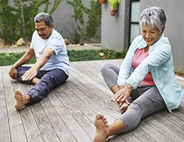 An older couple stretching outside.