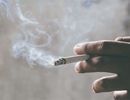 A hand holding a lit cigarette.