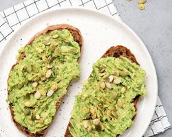 A white plate with toast slathered in avocado.