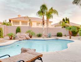 A pool area with plants and palm trees.