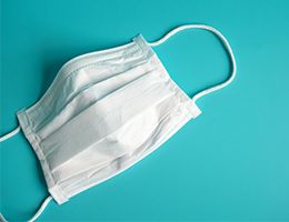 A paper face mask on a teal background.