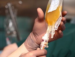 A hand reaches toward a bag of plasma.