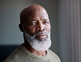 An older, bearded man looks at the camera.