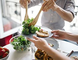 One person is putting a serving of salad on another person's plate.