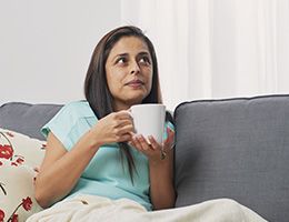 A woman on a couch holding a mug.