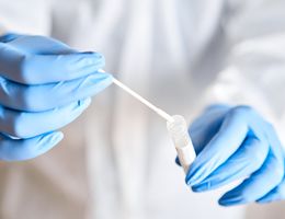 Gloved hands hold a lab vial and a swab.