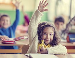 Grade-schooler raises her hand in a classroom.