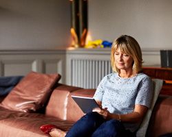 A woman on a leather couch reads her tablet