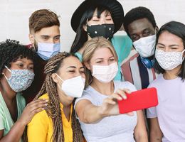 A group of teens in face masks pose for a selfie.
