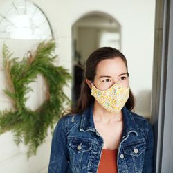 A woman answering the door wearing a face mask.