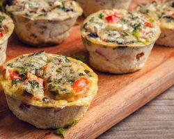 A cutting board with multiple salmon and veggie egg muffins.