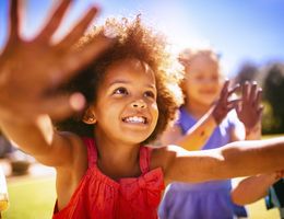 A smiling girl with muddy hands outstretched