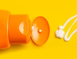 Sunscreen bottle with a squiggle of sunscreen on a yellow background