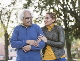 Older couple walking down a tree-lined street.