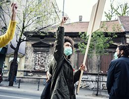 Protesters in a street, wearing masks and carrying signs.