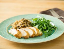 Asian chicken slices on a plate with greens and rice.