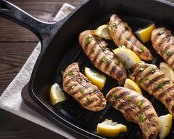 A cast iron with chicken and lemon wedges.