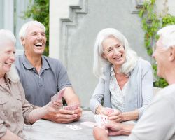 Four older adults sit at a table, laughing